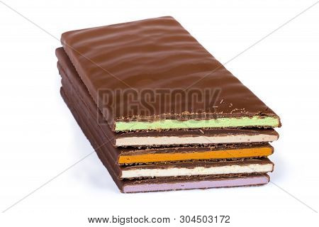 Stack Of Several Blocks Of The Milk Chocolate With Filling Different Colors, Cut At An Angle On A Wh
