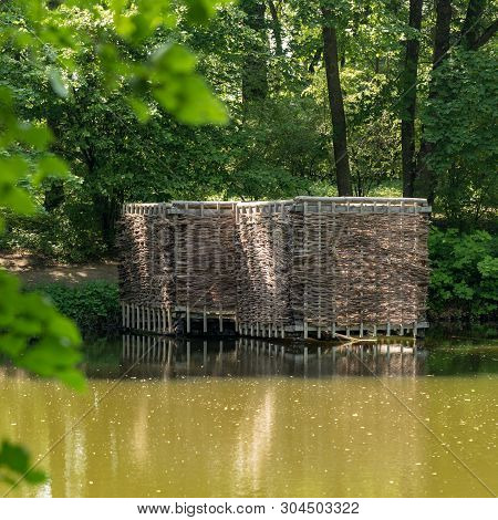 Wooden Building On The Shore Of The Pond. Wicker Building In The Forest.