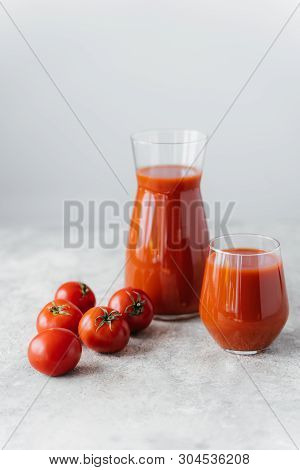 Ripe Fresh Red Tomatoes Near Two Glasses Of Squezeed Tasty Tomato Juice, Against White Background. I