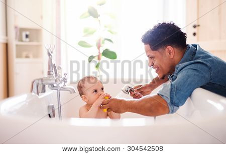 Father Washing Small Toddler Son In A Bathroom Indoors At Home.
