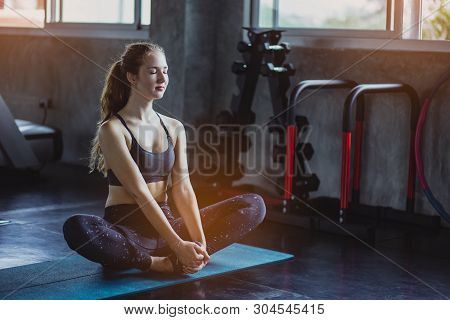 Woman At The Gym Doing Stretching Exercises And Smiling On The Floor.sport Background.