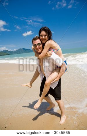 Hunk transporterar kvinna Piggyback stil Ath Beach