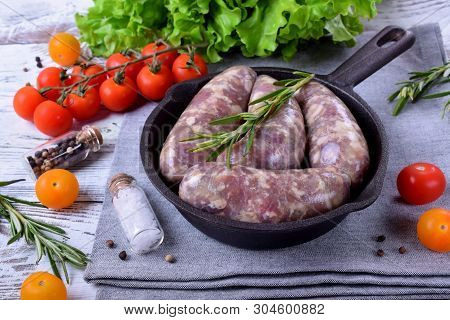 Raw Meat Sausages In A Natural Shell In A Cast Iron Pan Prepared For Grilling