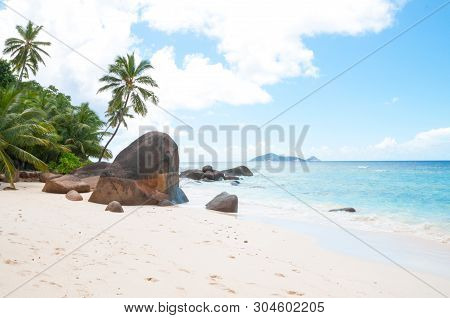 Beautiful Beach In Seychelles With Rocks And Palm Trees, Blue Indian Ocean And Picturesque Sky.