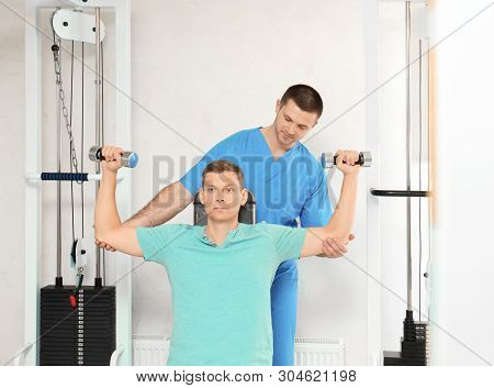 Patient Exercising Under Physiotherapist Supervision In Rehabilitation Center