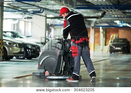 worker with machine cleaning floor in parking garage.