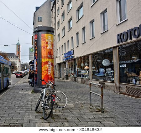 Urban Cityscape. Bicycles And Advertising Curbstone With Bus Stop And Shop Windows Of A Store In Bac
