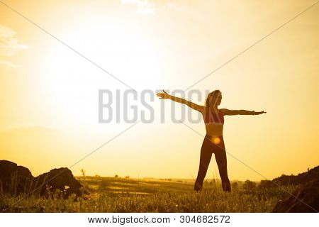 Young Woman Doing Stretching Outdoor. Warm up Exercise Against a Hot Beautiful Summer Sunset. Sport and Healthy Active Lifesyle Concept.