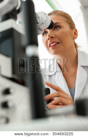 Pleasant Smiling Doctor Being Concentrated On Pictures In Device