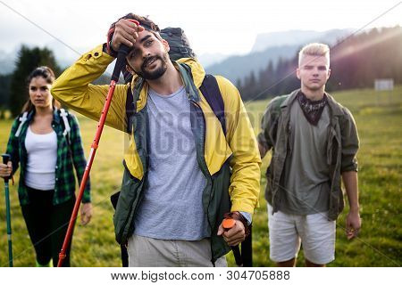 Gorup Of Friends Climbing Up Hill, With Backpacks And Climbing Stick