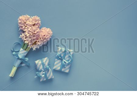 Blue Paper Background With Tied Bunch Of Pink Hyacinth Flowers And Wrapped Gift Boxes, Copy-space