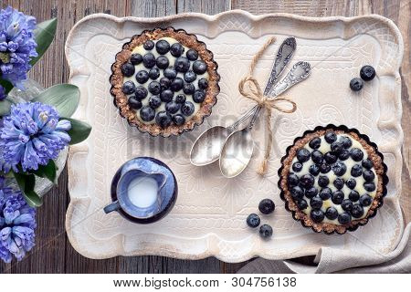 Top View On Wholegrain Blueberry Tarts With Vanilla Cream On A Ceramic Tray On Wood
