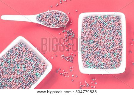 Colorful Nonpareils Cake Candy Sprinkles In Two White Rectangular Bowls And Spoon On Pink Background