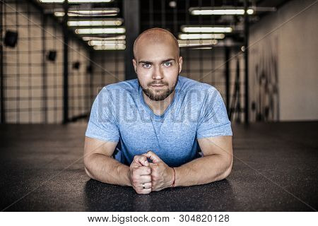 Portrait Of A Serious Sports Coach With A Bald Head. Resting In The Gym After Push-ups. Workout Was 