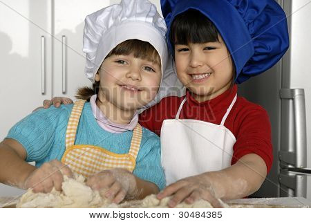 Due bambine cucinare una pizza in una cucina.Ragazzino in una cucina insieme.