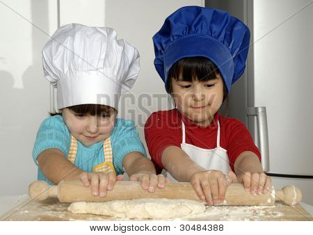 Due bambine cucinare una pizza in una cucina.Ragazzino in una cucina insieme.