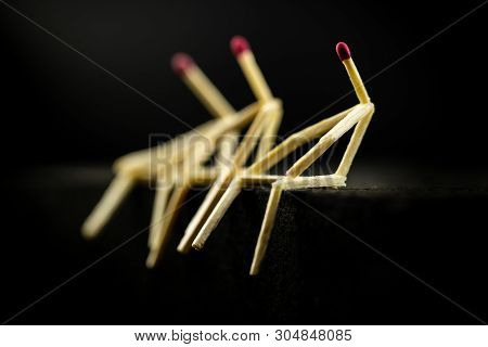 Image Of Three Men With Matchsticks Sitting In The Dark, One Of Them Sad And Erased. Concept Of Lone