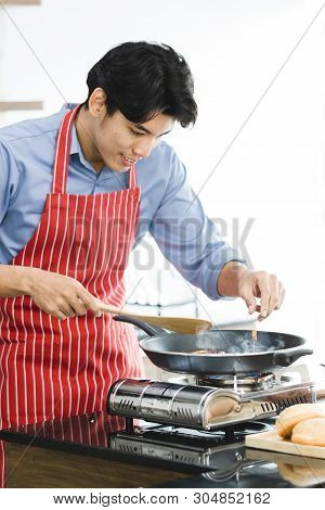 Close Up Shot Of Good Looking Asian Man Fried Hamburger In Pan On Stove, There Are Hamburger Ingredi