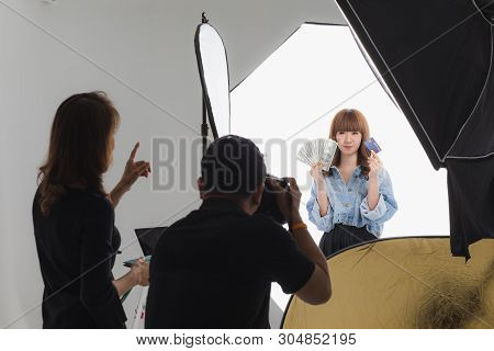 Photographer And Stylist Team Working On Studio Portrait Of Young Beautiful Asian Woman With Dark Br