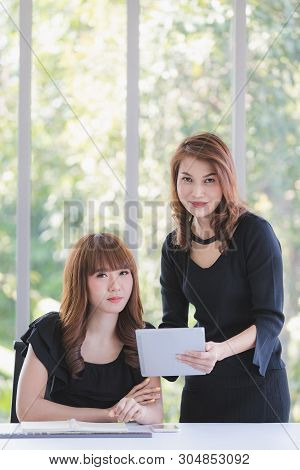Portrait Of Two Beautiful Asian Successful Businesswomen In Black Dresses Busily Working In Modern O