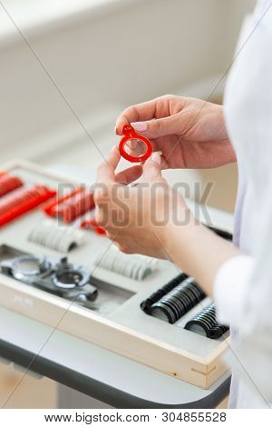 Curious Oculist With Accurate Hands Holding Lens In Red Frame