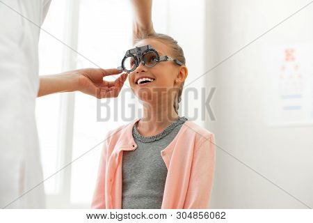 Beaming Cute Little Kid Calmly Sitting In Bright Cabinet