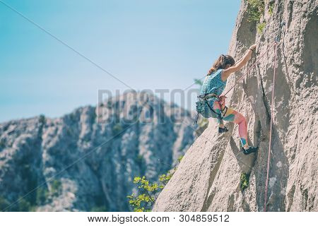 Rock Climbing And Mountaineering In The Paklenica National Park. A Woman Overcomes A Challenging Cli