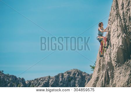 Rock Climbing And Mountaineering In The Paklenica National Park. A Woman Overcomes A Challenging Cli
