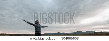 Wide View Image Of Young Man Celebrating Life Standing With His Arms Spread Widely Under A Glorious 