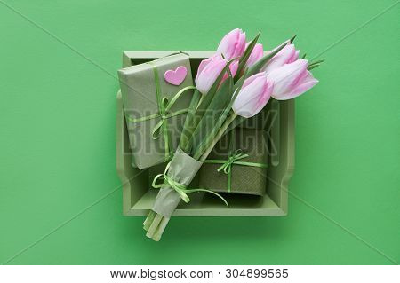 Springtime Green Paper Background With Pink Tulips, Wrapped Gift Boxes And Decorative Hearts In Wood