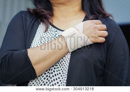 Asian Middle-aged Lady Woman Use Elastic Bandage To Treating De Quervain Syndrome At Hand And Finger