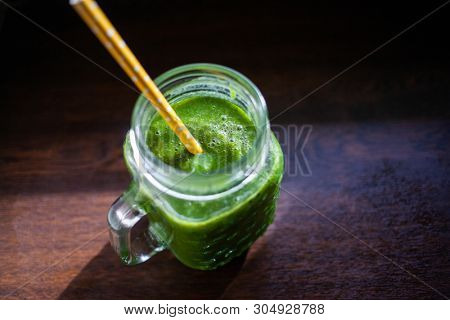 jar with green cold-pressed juice, wooden background. Healthy eating, detoxing, juicing body cleancing concept 