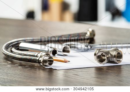 Water Braided Metal Hose And Hosepipe Fittings Laying On Table. Close Up Flexible Hydraulic System. 