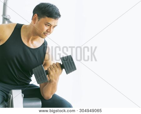 Soft Focus The Young Man Sat On The Exercise Machine And Was Lifting The Concentration Dumbbell Curl