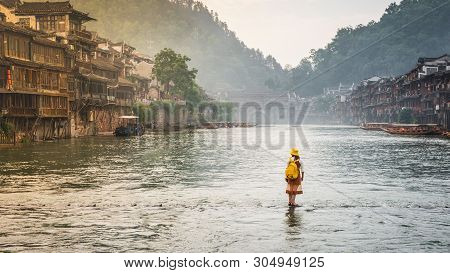 Woman On Steeping Stones Bridge Over Tuo Juang River Seems Walking On Water In Fenghuang Ancient Tow