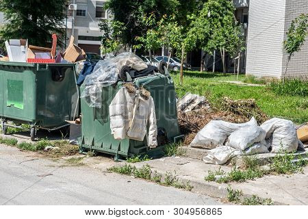 Garbage In City, Big Pile Of Overflowing Garbage And Junk With Jacket And Clothes On The Dumpster Ca