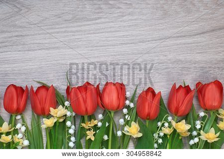 Bunch Of Red Tulips, Daffodils And Lily Of The Valley Flowers On Light Wooden Background. Space For 