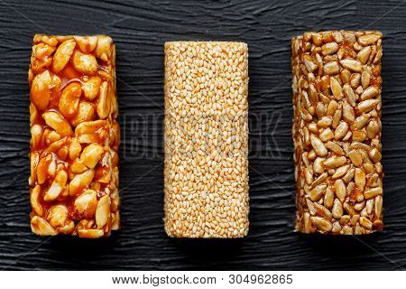 Cereal Granola Bar With Peanuts, Sesame And Sunflower Seeds On A Cutting Board On A Dark Stone Table