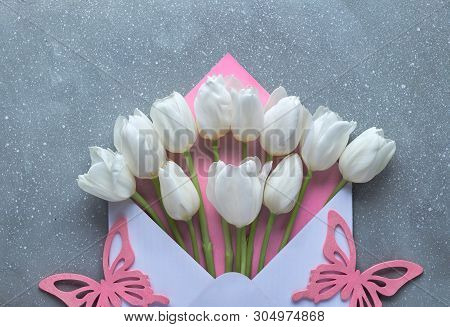 Springtime Flat Lay, White Tulips In White And Pink Envelope On Grey Textured  Background With Decor