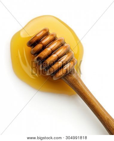 Top view of wooden honey dripper in the honey puddle isolated on white