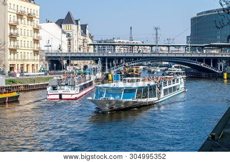 Berlin, Germany April 6, 2019: Pleasure Boats With People On The Spree River In Berlin With The Rail