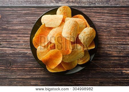 Potato Chips Over Wooden Background. Salty Crispy Snack. Isolated Chips.