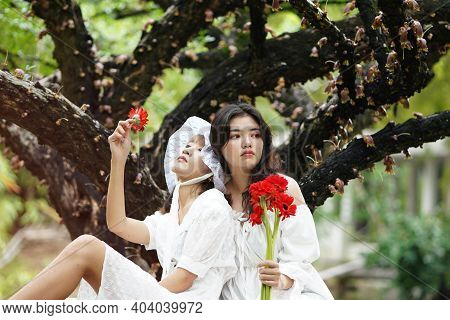 Two Girls Chilling Under The Tree With Red Gerbera Flower