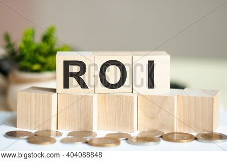 Concept Word Roi On Wooden Blocks On Beautiful Background From Dollar Bills. The Word Roi On Wood Cu