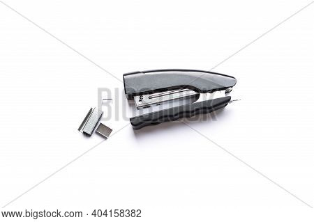 Black Stapler With Metal Staples On White Background.