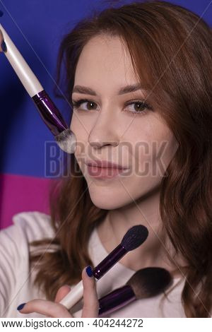 Charming Brunette Woman In White T-shirt With Makeup Brushes Isolated On Colorful Blue And Pink Back