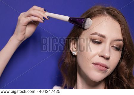 Charming Brunette Woman In White T-shirt With Makeup Brushes Isolated On Colorful Blue Background. P