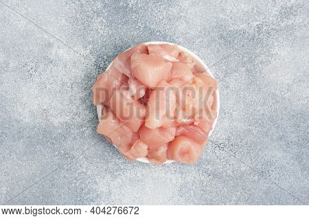 Raw Chicken Fillet Breasts Cut Into Pieces In A Plate, Gray Background, Copy Space, Top View.
