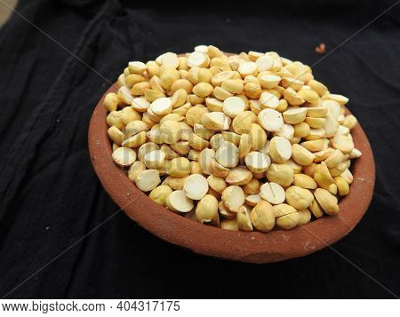 Roasted Gram Pile In A Red Color Plastic Cup And Traditional Sand Bowl With Scattered On Black Backg