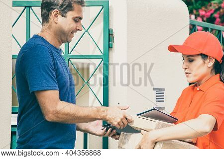Caucasian Man Receiving His Order From Deliverywoman. Latin Courier Delivering Order, Holding Parcel